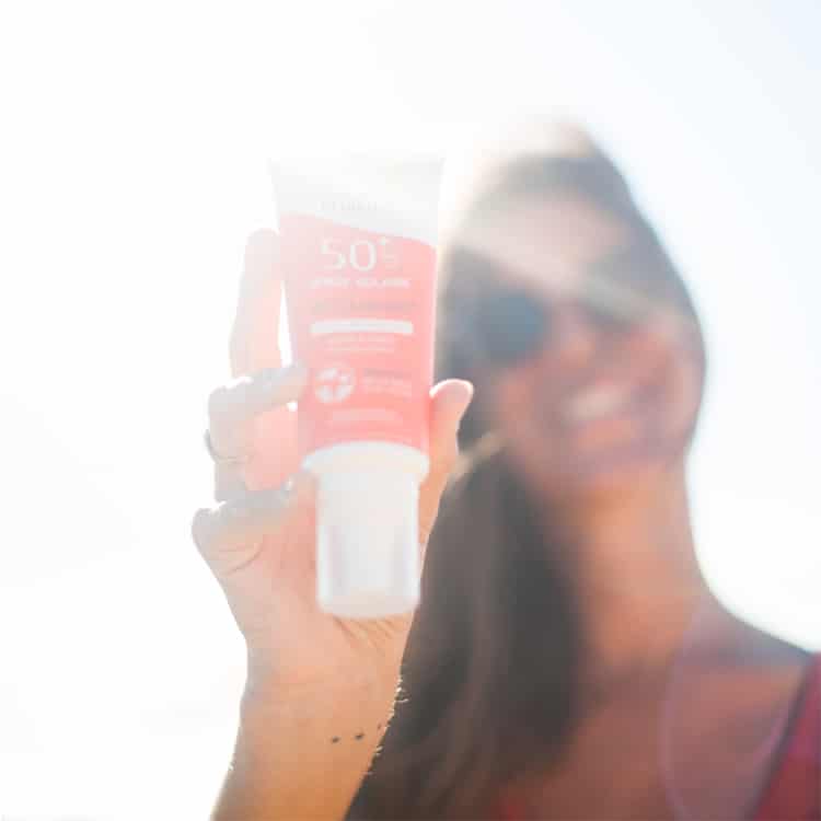 femme qui tient du spray solaire bio